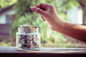 Hand putting coin into jar